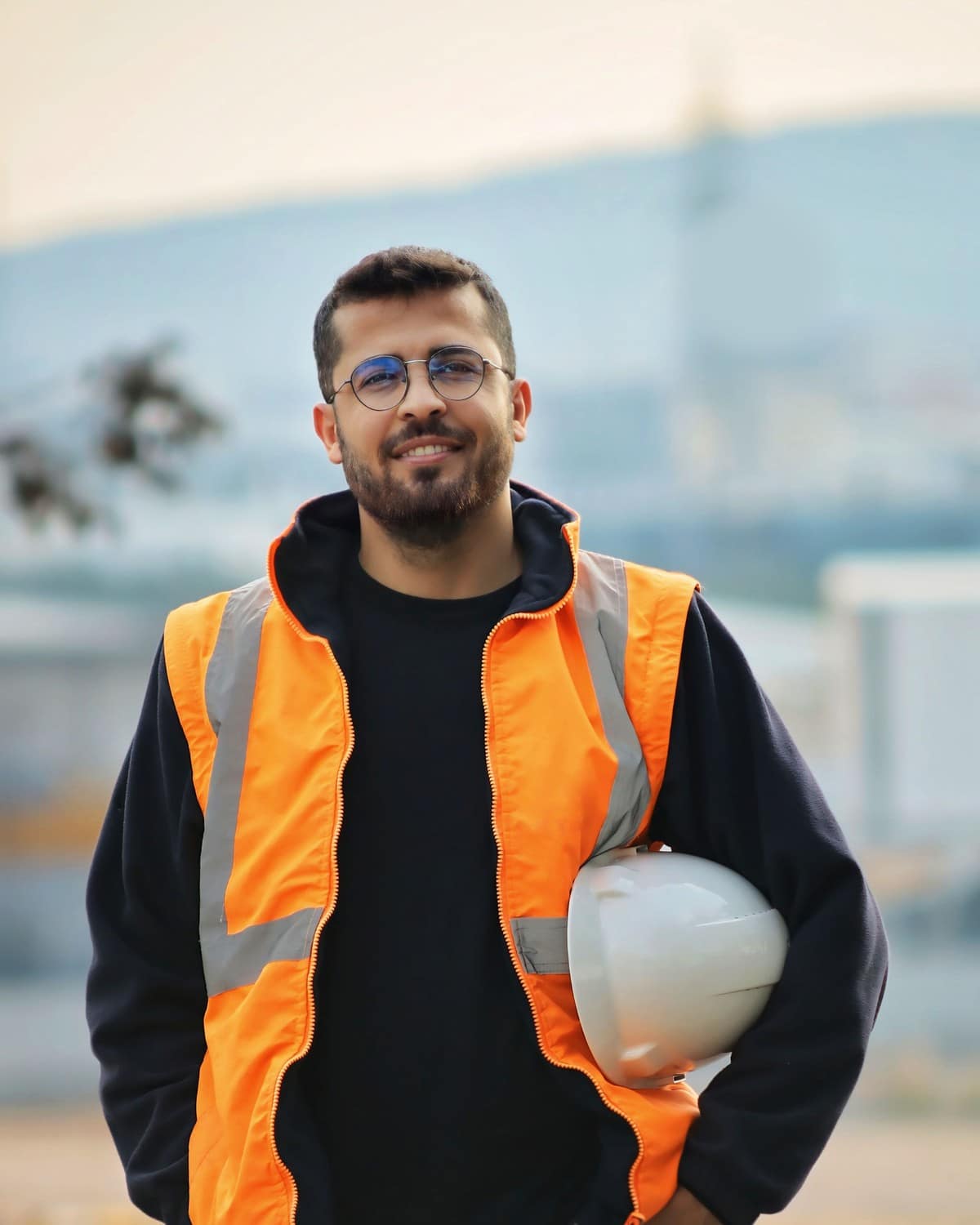 Trabalhador com colete refletivo laranja e capacete de segurança debaixo do braço